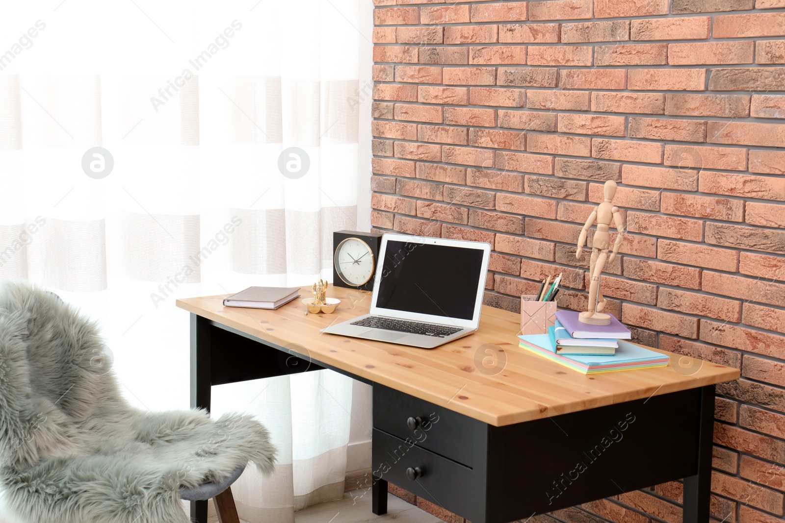 Photo of Stylish workplace interior with laptop on table near brick wall. Space for text