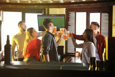 Photo of Group of friends celebrating victory of favorite football team in sport bar