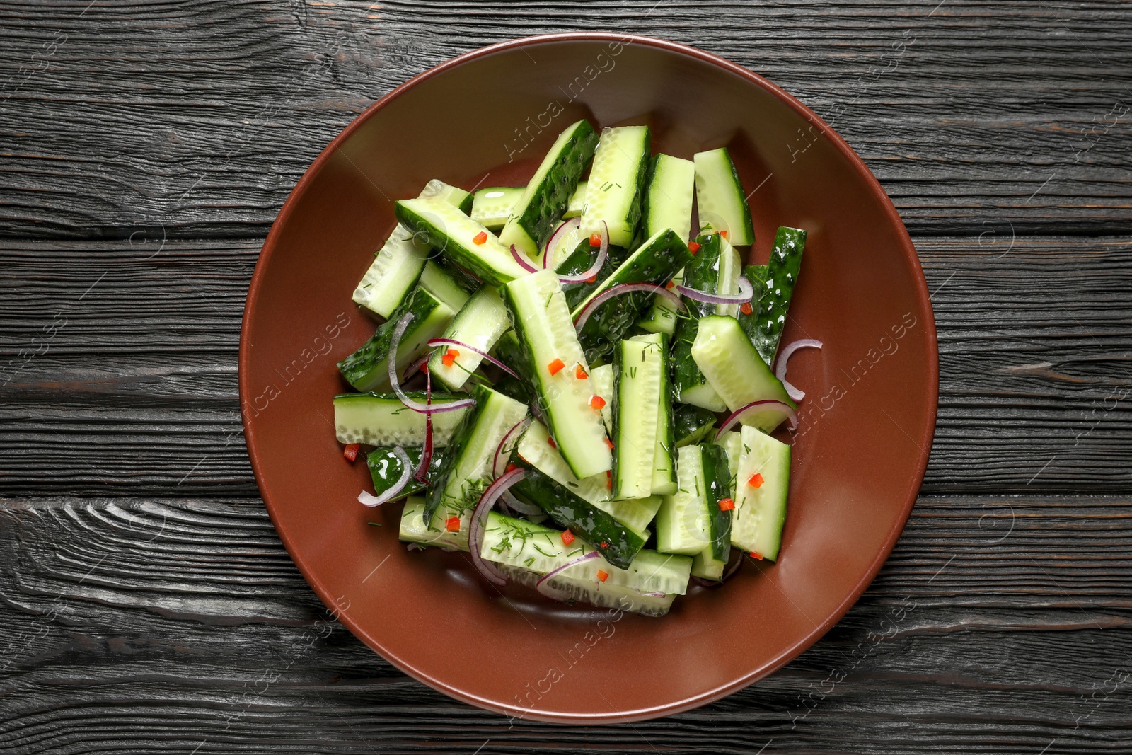 Photo of Plate with delicious cucumber salad on wooden background, top view