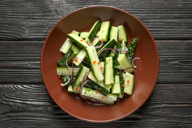 Photo of Plate with delicious cucumber salad on wooden background, top view