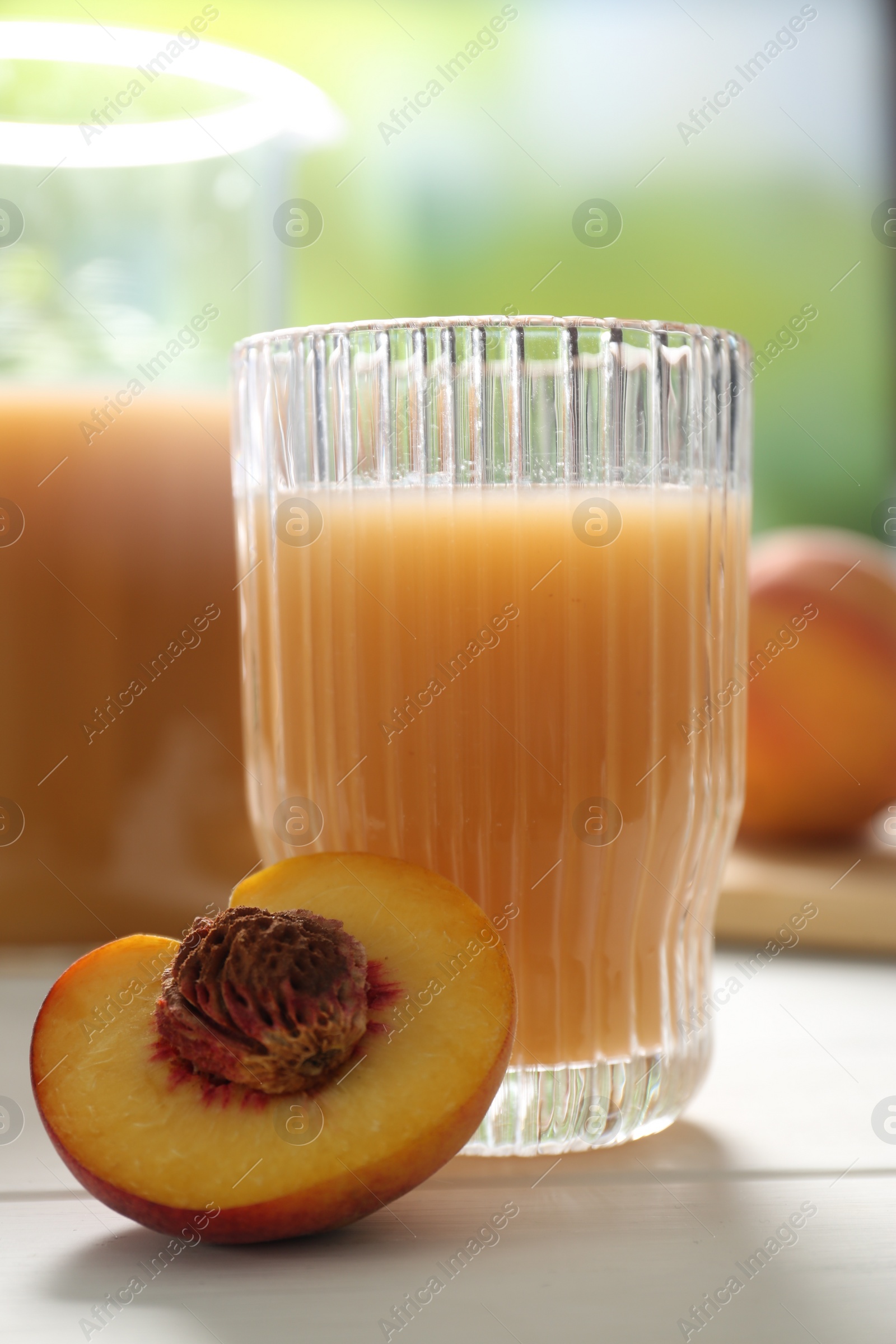Photo of Glass of peach juice and fresh fruit on white wooden table, closeup