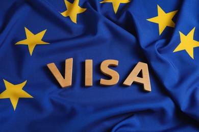 Photo of Word Visa made of wooden letters on European Union flag, above view
