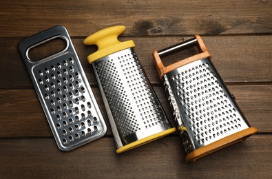 Different modern graters on wooden table, flat lay
