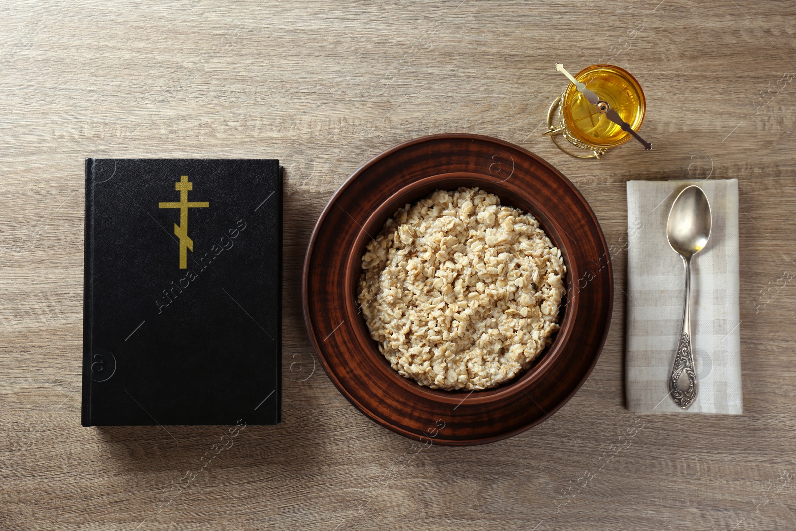 Photo of Bible, oatmeal porridge and spoon on wooden table, flat lay. Lent season