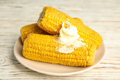 Delicious boiled corn with butter on white wooden table