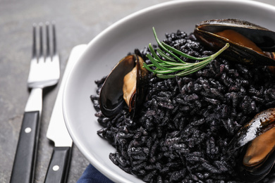 Delicious black risotto with seafood in bowl on table, closeup