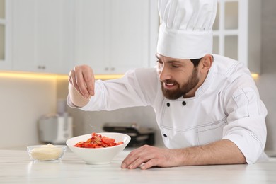 Photo of Professional chef adding grated cheese into delicious spaghetti at marble table