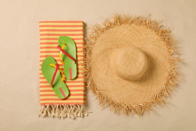 Beach towel, hat and flip flops on sand, flat lay