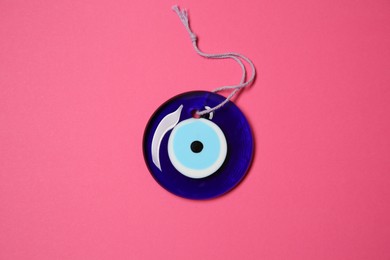 Photo of Evil eye amulet on pink background, top view