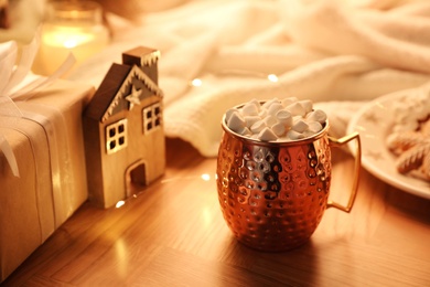 Cup of hot drink with marshmallows and Christmas decor on wooden table