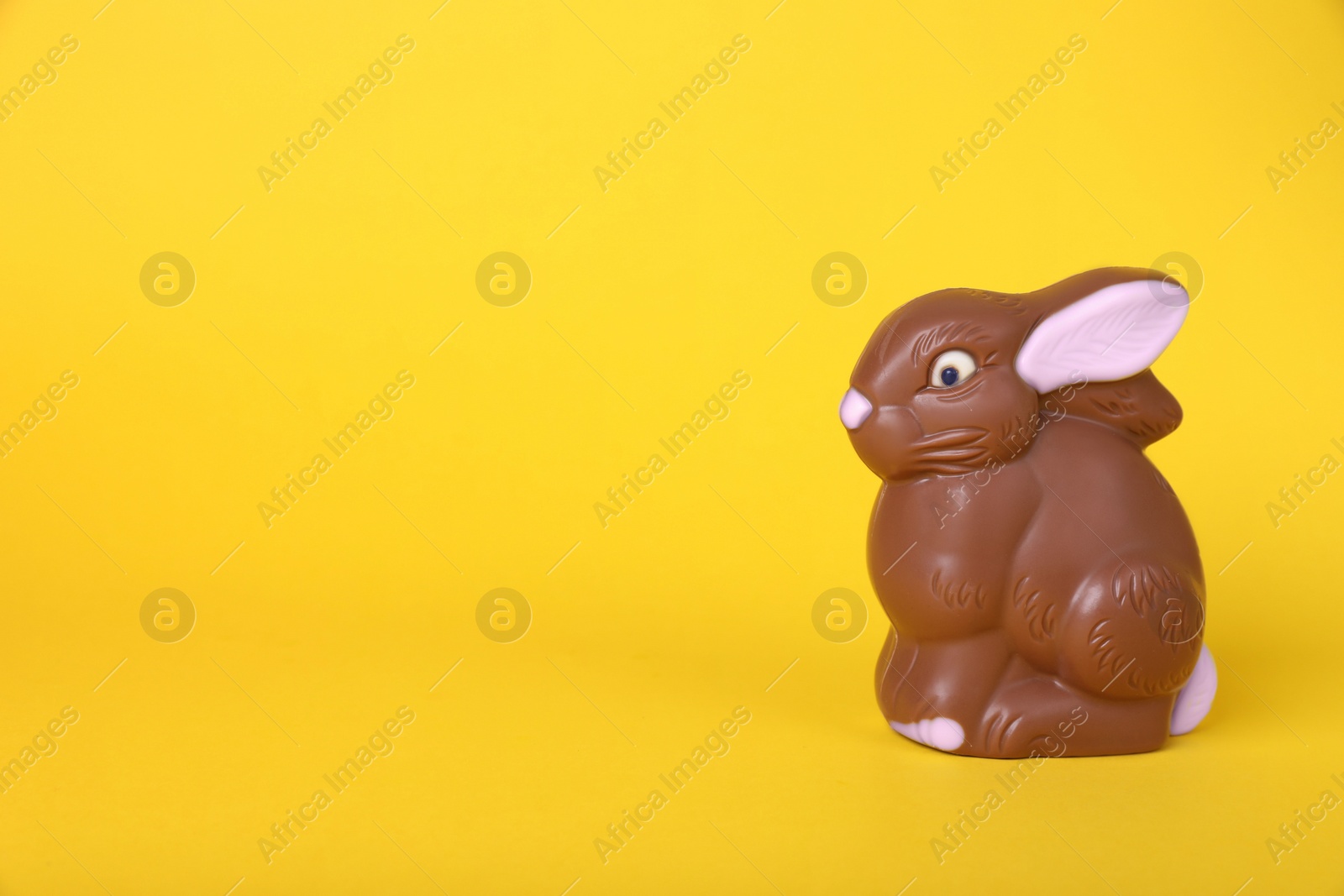 Photo of Chocolate bunny on yellow background, space for text. Easter celebration