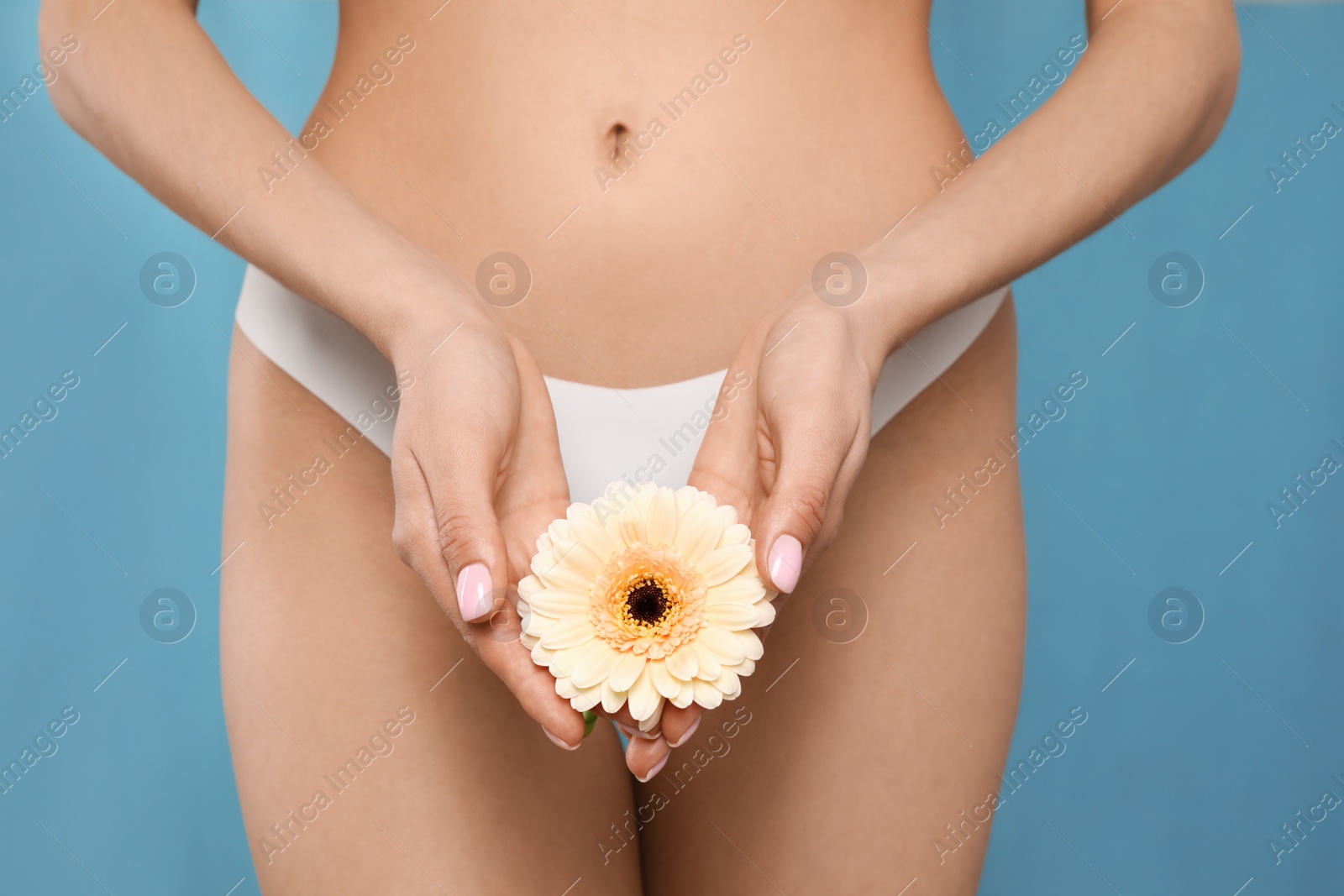 Photo of Woman in white panties with gerbera flower on light blue background, closeup
