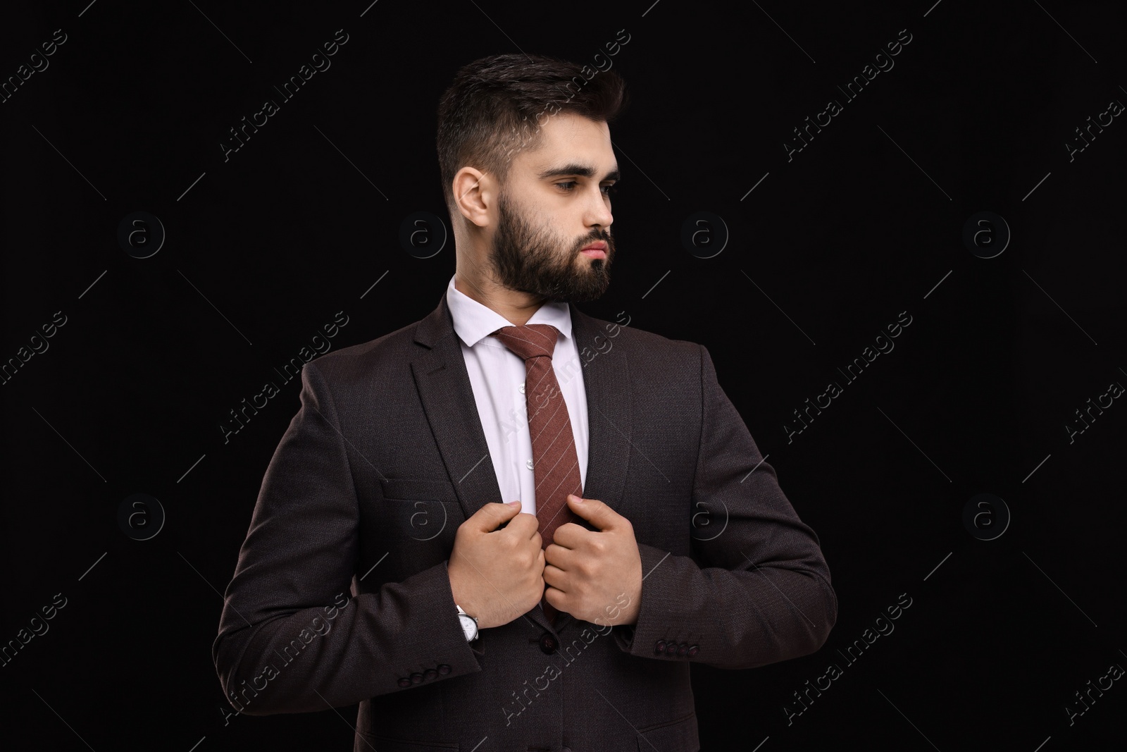 Photo of Handsome businessman in suit and necktie on black background