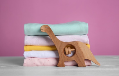 Stack of children's clothes and toy on white wooden table