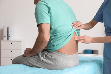 Orthopedist examining man's back in clinic, closeup. Scoliosis treatment