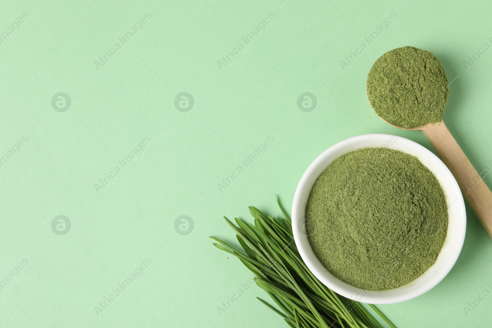 Photo of Wheat grass powder and fresh sprouts on green table, flat lay. Space for text