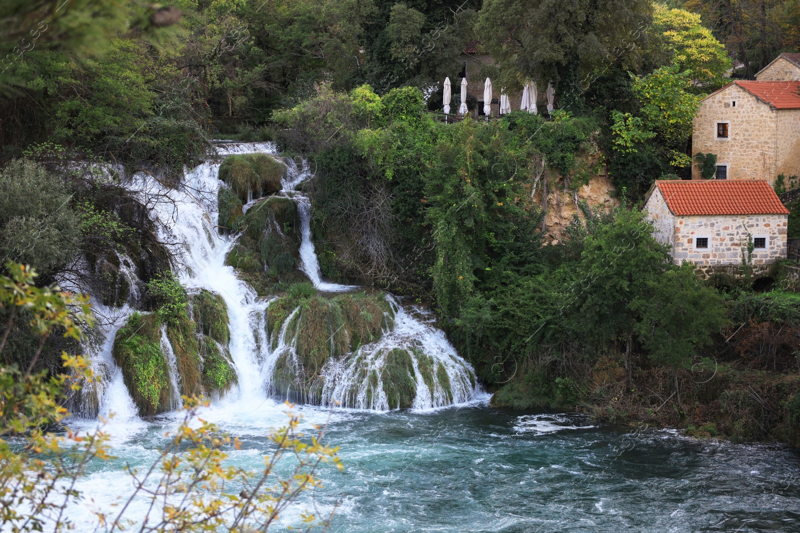 Photo of Picturesque view of beautiful waterfall and buildings outdoors