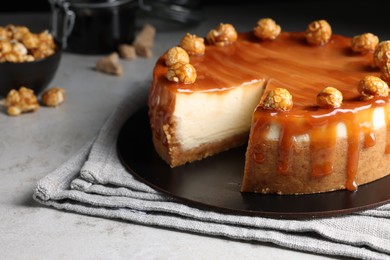 Sliced delicious cheesecake with caramel and popcorn on light grey table, closeup