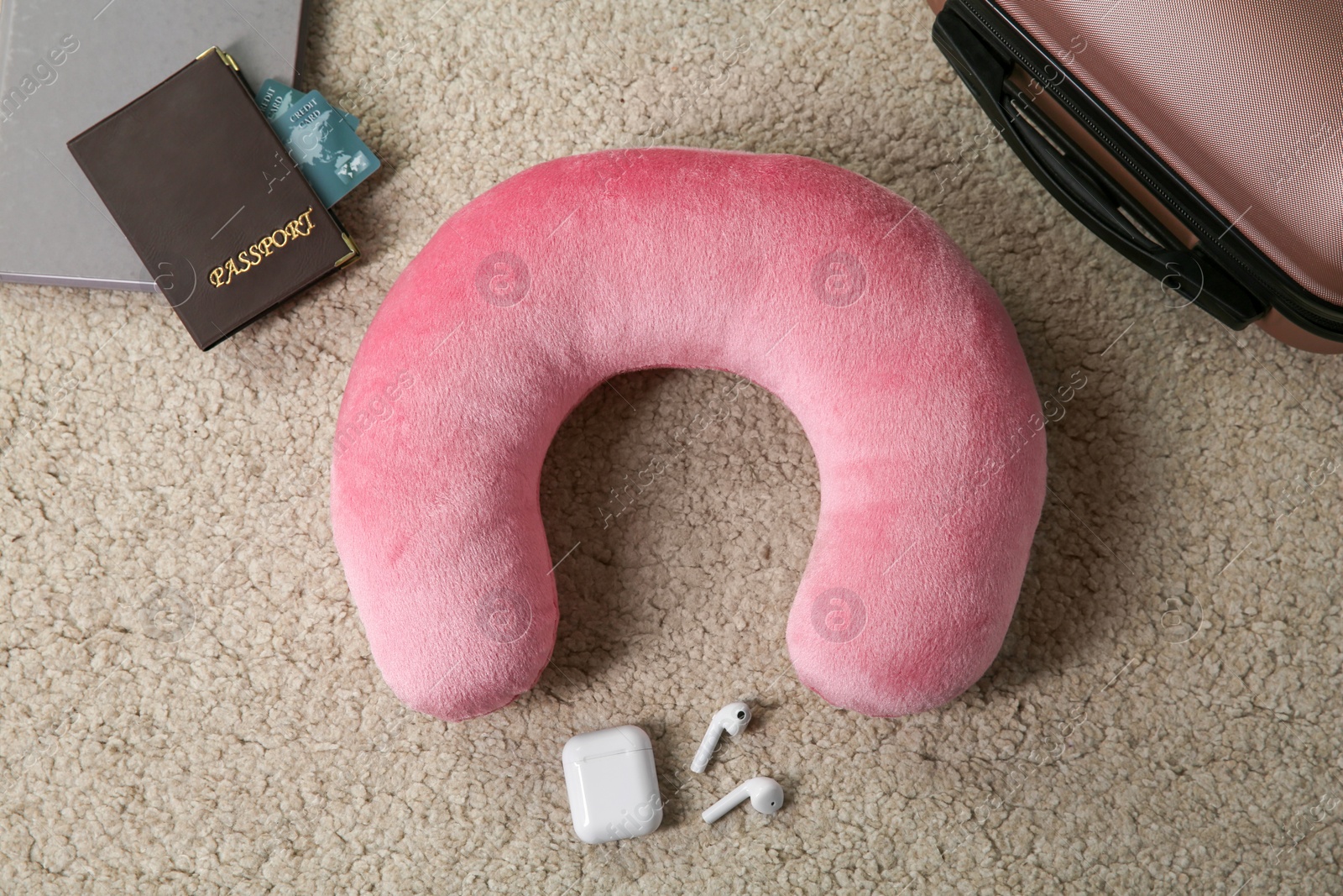 Photo of Flat lay composition with pink travel pillow on beige rug