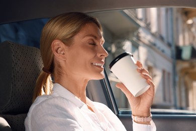 Photo of To-go drink. Happy woman drinking coffee in car