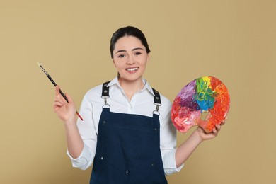 Photo of Woman with painting tools on beige background. Young artist