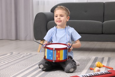 Little boy playing toy drum at home