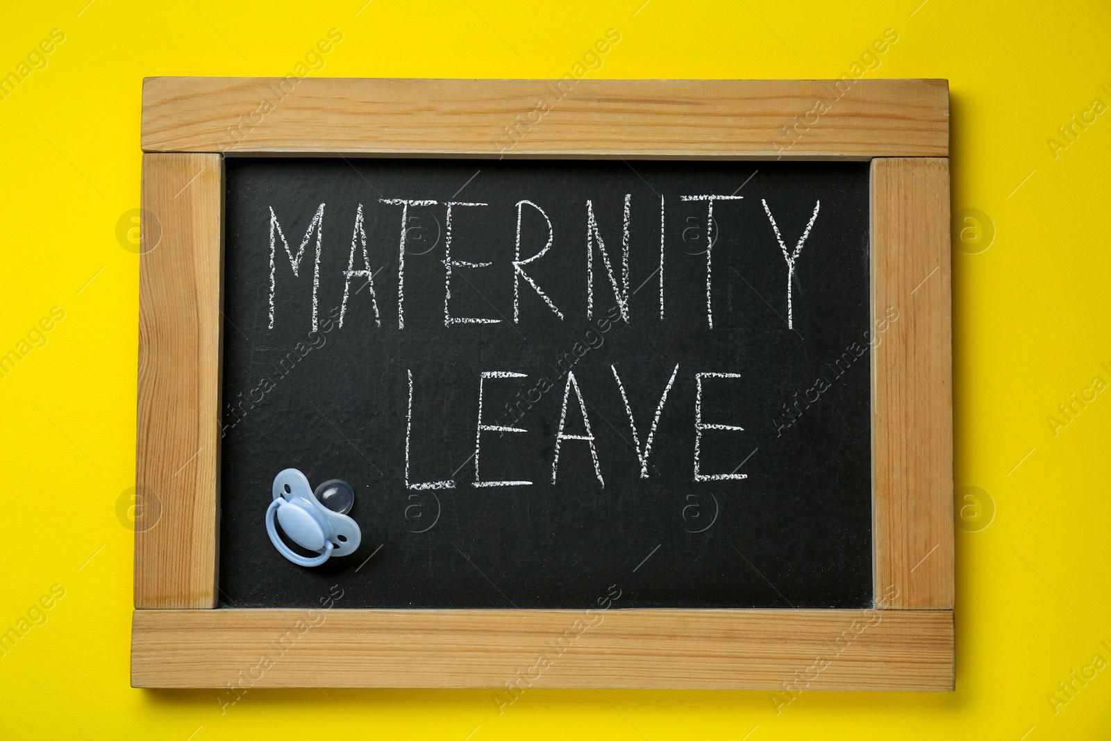 Photo of Small chalkboard with phrase Maternity Leave and baby pacifier on yellow background, top view