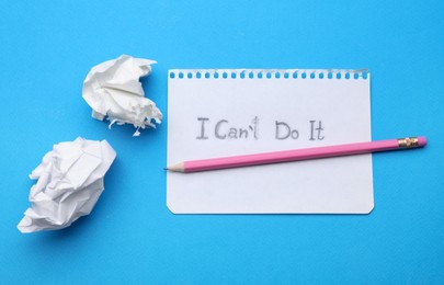 Photo of Motivation concept. Paper with changed phrase from I Can't Do It into I Can Do It by erasing letter T on light blue background, top view