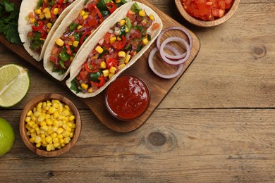 Photo of Tasty tacos with vegetables on wooden table, flat lay. Space for text