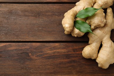 Photo of Fresh ginger with leaves on wooden table, top view. Space for text