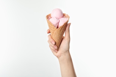 Photo of Woman holding delicious ice cream in waffle cone on white background, closeup