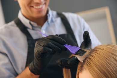 Photo of Professional hairdresser dying hair in beauty salon, closeup