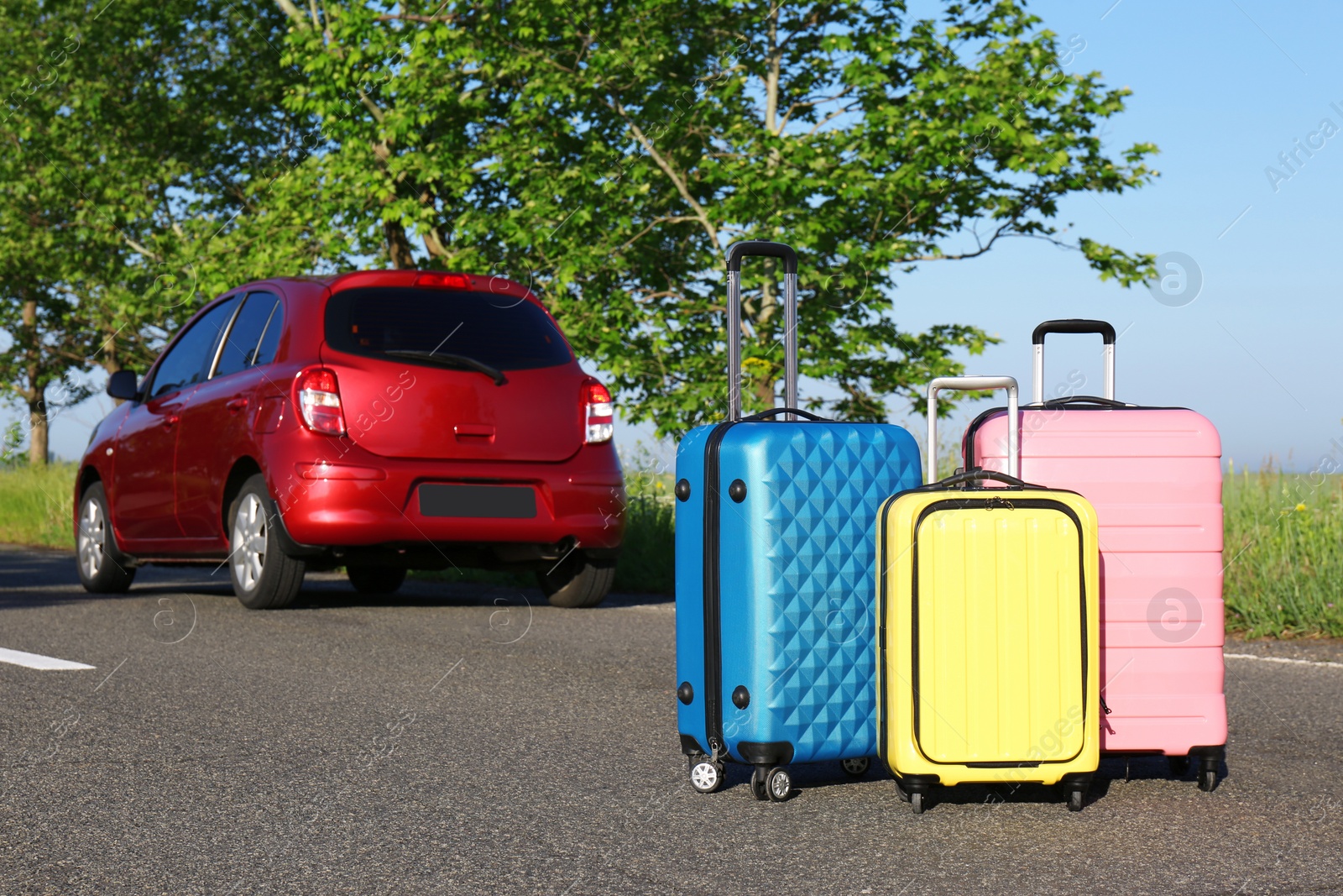 Photo of Color suitcases near family car on highway. Summer vacation