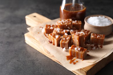 Photo of Tasty candies, caramel sauce and salt on grey table