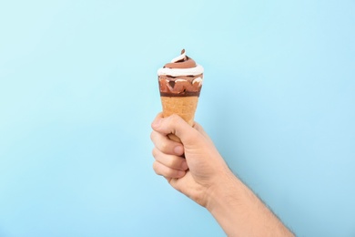 Photo of Man holding yummy ice cream on color background. Focus on hand