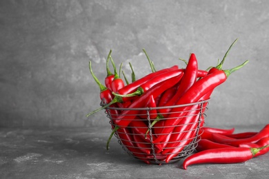 Photo of Basket with ripe chili peppers on grey background