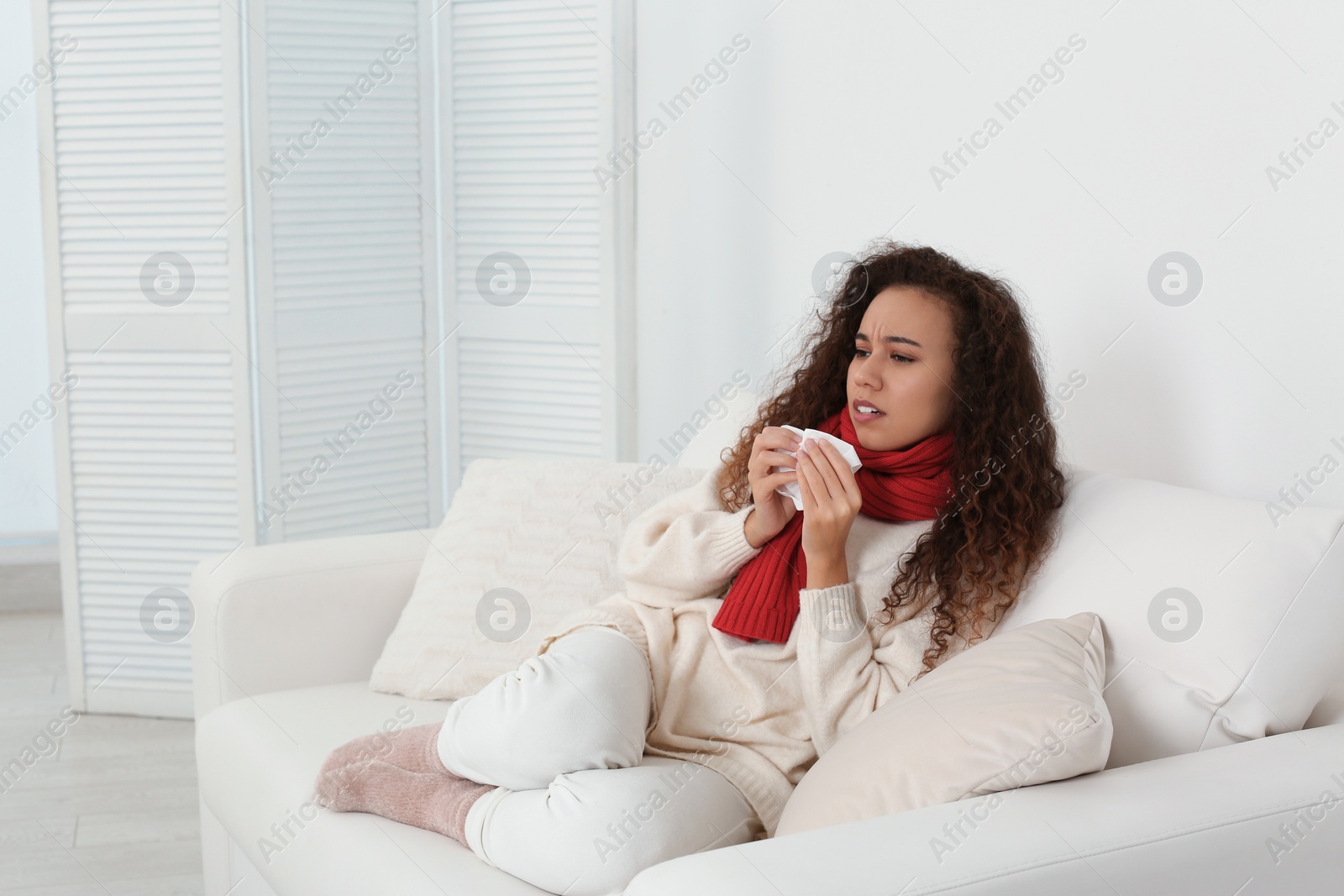 Photo of Sick African American woman sneezing at home, space for text