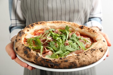 Photo of Woman holding tasty pizza with meat and arugula on white background, closeup