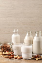 Photo of Different nut milks on wooden table. Space for text