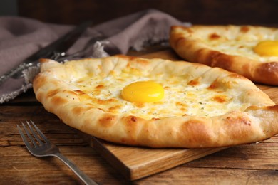 Photo of Fresh homemade khachapuri with cheese and egg on wooden table, closeup