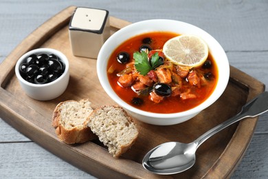 Meat solyanka soup with sausages, olives and vegetables in bowl served on grey wooden table