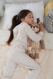 Photo of Cute girl in pajamas sleeping with toy deer at home