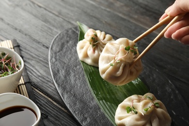 Photo of Woman eating tasty baozi dumplings at table, closeup