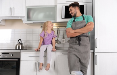 Photo of Young man and his daughter in kitchen with modern ovens
