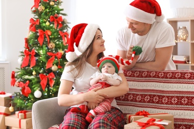 Photo of Happy couple with baby in Christmas hats at home