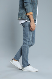 Photo of Young man in stylish jeans on grey background, closeup