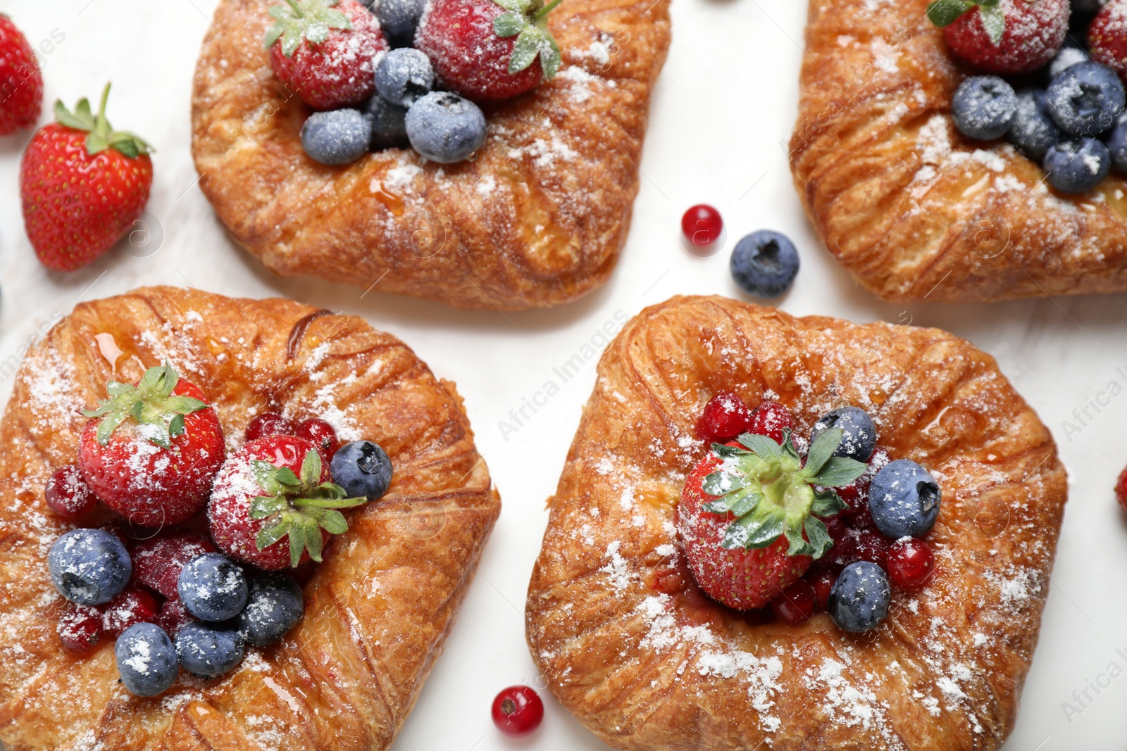 Photo of Fresh delicious puff pastry with sweet berries on white marble table, flat lay