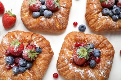 Fresh delicious puff pastry with sweet berries on white marble table, flat lay