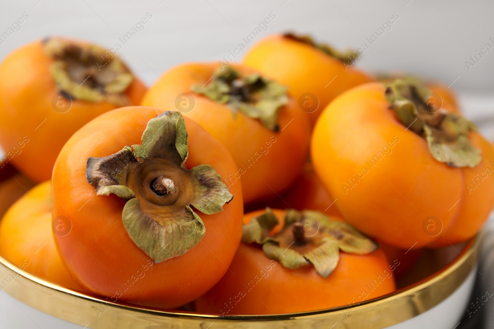 Photo of Bowl with delicious ripe juicy persimmons, closeup