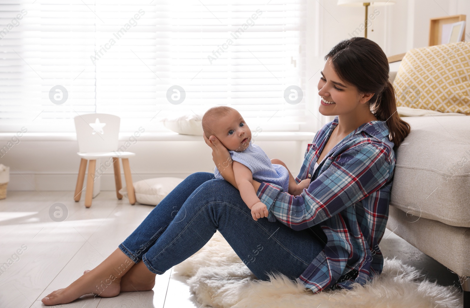 Photo of Happy young mother with her cute baby on floor at home